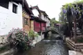Traditionelles chinesisches Dorf mit Kanal, Steinbrücke, Rosen und Glyzinien.