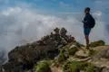 Wanderer auf einem Berggipfel mit Blick auf die Wolken.