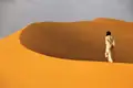 Person in traditioneller Kleidung in einer Wüstenlandschaft.