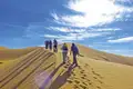 Wandergruppe besteigt eine Sanddüne.