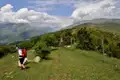Wanderer mit rotem Rucksack auf einem Bergpfad mit Blick auf eine Berglandschaft.