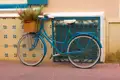 Blaues Fahrrad mit Blumenkorb vor gemusterter Wand.