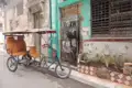 Ein Fahrradtaxi, ein typisches Transportmittel in Kuba, parkt vor einem bunten Haus.