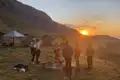 Wanderer am Lagerfeuer bei Sonnenuntergang in den Bergen.