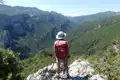 Wanderer auf einem Felsvorsprung mit Blick auf eine bewaldete Schlucht.