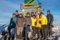 Wandergruppe feiert die erfolgreiche Besteigung des Uhuru Peak, dem höchsten Punkt des Kilimandscharo in Tansania.