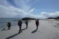 Wanderer mit Rucksäcken auf einer Strandwanderung.
