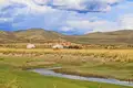 Traditionelle mongolische Jurten in einer hügeligen Landschaft mit grasenden Pferden und einem Fluss.