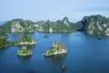 Panoramablick auf die Kalksteininseln und das ruhige Wasser der Halong-Bucht mit traditionellen Dschunken.