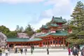 Traditionelle japanische Architektur mit grünen Ziegeldächern und Kirschblüten im Hintergrund.