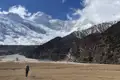 Wanderer in einer hochgelegenen Landschaft mit Blick auf schneebedeckte Berge und Gletscher.