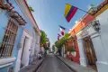 Farbenfrohe Kolonialgebäude säumen eine Straße in Cartagena. Verschiedene Flaggen, darunter die kolumbianische, französische und kanadische, wehen im Wind.