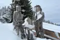 Zwei Holzfiguren, bedeckt mit Schnee, am Aussichtspunkt.