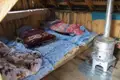 Schlafbereich in einer einfachen Hütte mit Ofenheizung.
