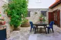 Innenhof mit Steinboden, Tisch, Stühlen und Pflanzen.