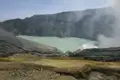 Ausblick auf den Kratersee eines aktiven Vulkans mit sichtbaren Rauchschwaden.