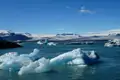Eisberge im Vordergrund und ein Gletscher im Hintergrund.