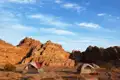 Zwei Zelte in einer Wüstenlandschaft mit Felsformationen im Hintergrund.