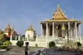 Ein traditionelles Tempelgebäude mit goldenen Verzierungen und ein Modell von Angkor Wat, welches die kulturelle Bedeutung der Tempelanlage unterstreicht.