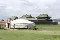 Traditionelle mongolische Jurte vor einem Tempelgebäude.