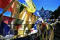 Gebetsfahnen im Wind mit Berggipfel im Hintergrund.