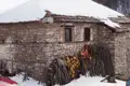 Verschneites Steinhaus mit Brennholzvorrat.