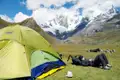 Wanderer ruht im Basislager vor dem Zelt mit Blick auf die schneebedeckten Berge.