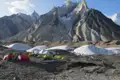 Basislager mit Zelten in einer hochalpinen Umgebung, umgeben von Gletschern und Bergen.