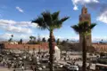 Platz in Marrakesch mit Minarett und Palmen.