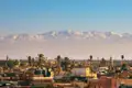 Blick auf die Dächer von Marrakesch mit dem schneebedeckten Atlasgebirge im Hintergrund.