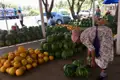 Marktstand mit Wassermelonen und Melonen. Eine Verkäuferin sortiert die Früchte.