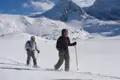 Zwei Schneeschuhwanderer durchqueren eine verschneite Berglandschaft.