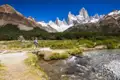 Wanderer überquert einen Bach in Patagonien mit dem Fitz Roy im Hintergrund.