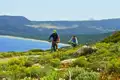 Mountainbiker auf einem Küstenpfad mit Blick auf das Meer und die Berge.