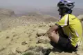 Radfahrer macht Pause in einer felsigen Wüstenlandschaft.