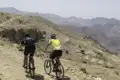 Zwei Mountainbiker auf einem Bergpfad in der Wüste.