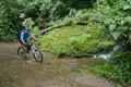 Mountainbiken im Regenwald: Durchquerung eines Baches.