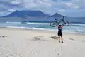 Radfahrer am Strand mit dem Tafelberg im Hintergrund.