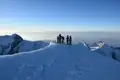 Bergsteiger auf einem verschneiten Berggipfel.