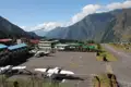 Flugzeuge stehen auf dem Rollfeld eines Flughafens, der sich inmitten einer bergigen Landschaft befindet.