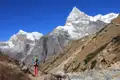 Wanderer auf einem Himalaya-Pfad mit Blick auf schneebedeckte Gipfel.