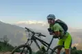 Mountainbikerin macht Pause auf einem Bergpfad mit Blick auf die Berge.