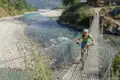 Radfahrer auf einer Hängebrücke über einen Fluss.