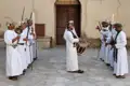 Omanische Männer in traditioneller Kleidung führen einen Schwerttanz und spielen Trommel vor dem Nizwa Fort.