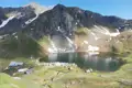 Alpenpanorama mit Bergsee und Hütte.