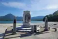 Statue am Seeufer mit Bergkulisse.