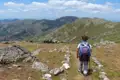 Wanderer auf einem Bergpfad. Im Hintergrund eine bergige Landschaft.