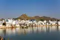 Heiliger See in Pushkar mit den umliegenden Gebäuden und Hügeln im Hintergrund.