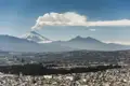 Der Vulkan Cotopaxi mit Rauchfahne über der Stadt.
