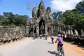 Kambodscha Radreise. Radfahrer auf einer Reise durch Angkor Thom, passieren das Südtor mit den charakteristischen Gesichtern und den steinernen Wächterfiguren.